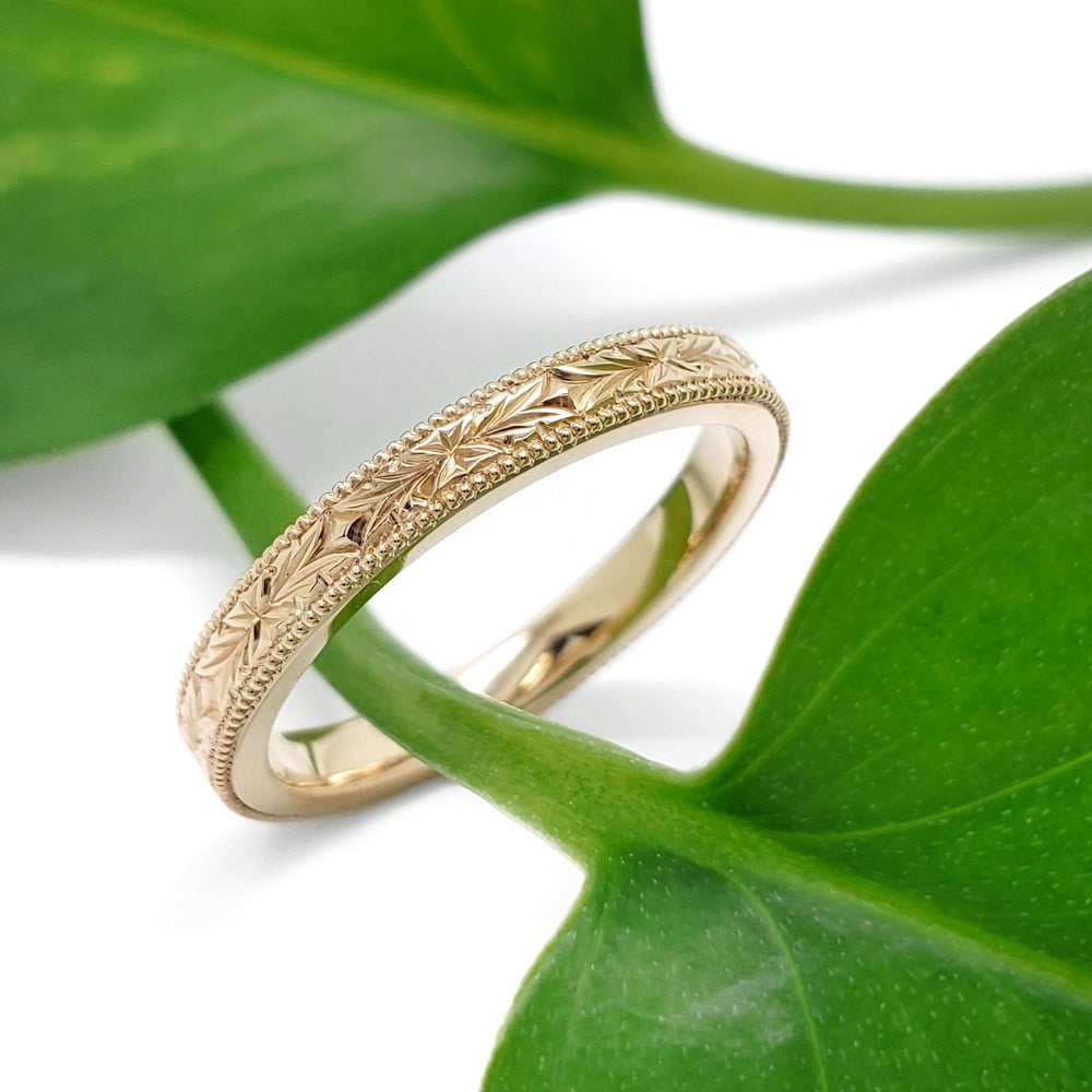 Handcrafted 14kt yellow gold wedding ring shown with engraved floral band on plant stem