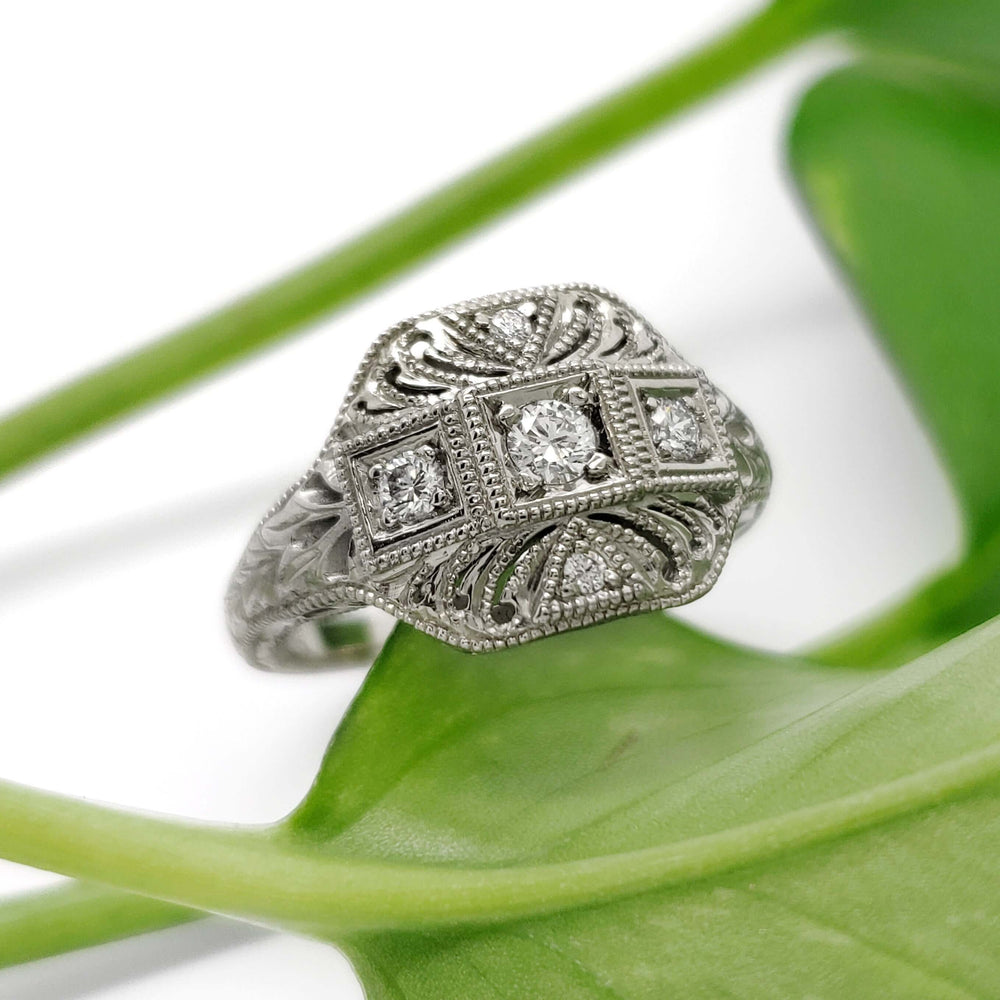 Handcrafted 19kt white gold diamond ring with vintage-inspired engraving on a green leaf