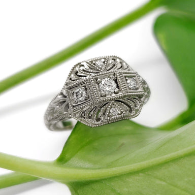 Handcrafted 19kt white gold diamond ring with vintage-inspired engraving on a green leaf