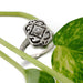 Handcrafted Edwardian diamond ring in white gold beside green leaves