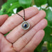 Hand holding 14kt white gold pendant with blue sapphire and diamond halo