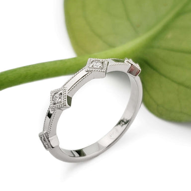 Handcrafted 14kt white gold diamond wedding ring with millgrain, shown with a leaf