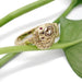 Handcrafted gold snake ring with champagne diamond and rubies, shown on green leaf