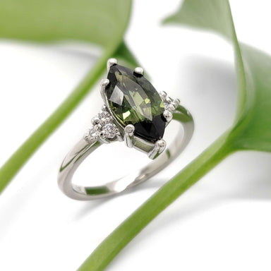 Handcrafted marquise green sapphire and diamond ring in white gold, styled with greenery