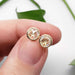 Hand holding rose cut moissanite stud earrings in 14kt yellow gold
