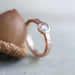 Handcrafted rose gold diamond ring with hammered band beside an acorn