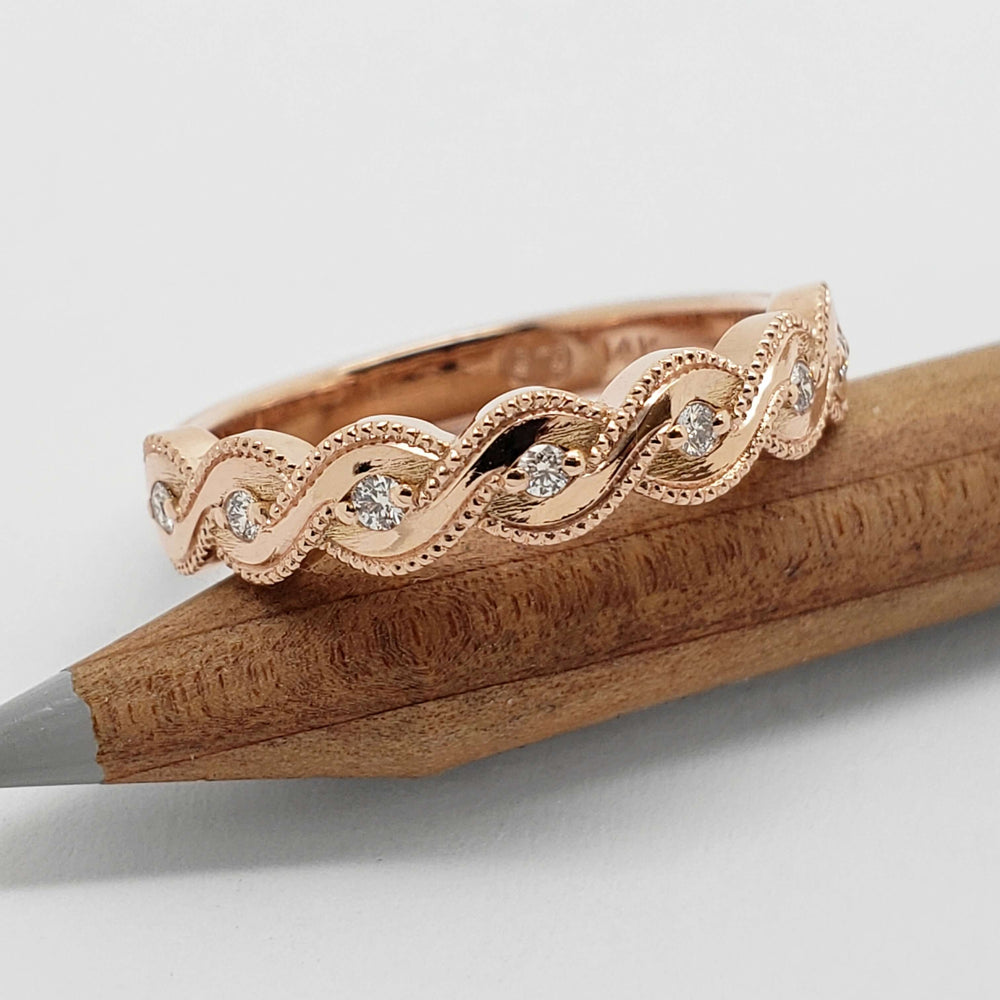 Handcrafted rose gold diamond wedding band with twisted millgrain on wood