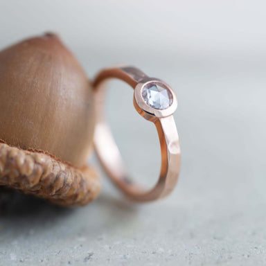 Handcrafted rose gold engagement ring with rose cut diamond beside an acorn