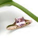 Handcrafted rose gold ring with cushion cut pink sapphire beside a green leaf