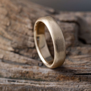 Handcrafted rose gold wedding ring with brushed texture on rustic wood