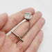 Hand holding sterling silver tie tack with concrete texture and chain, artisanal detail visible
