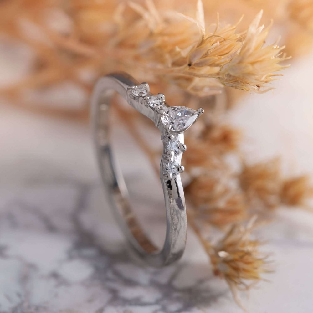 Handcrafted white gold chevron diamond ring with pear and round diamonds, styled with dried flowers