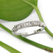 Handcrafted white gold diamond wedding ring with floral engraving, shown on a leaf background