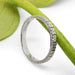 Handcrafted white gold floral wedding ring resting on a green stem
