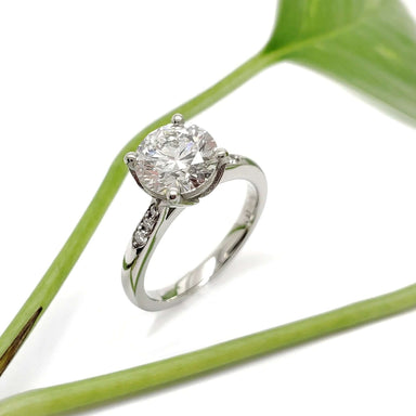 Handcrafted white gold lab diamond engagement ring with pave-set band, styled with greenery