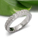Handcrafted white gold leaf motif wedding band with diamonds, beside green leaf