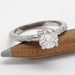 Handcrafted white gold moissanite engagement ring resting on a pencil