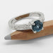 Handcrafted white gold ring with round blue Montana sapphire and diamond accents on a pencil