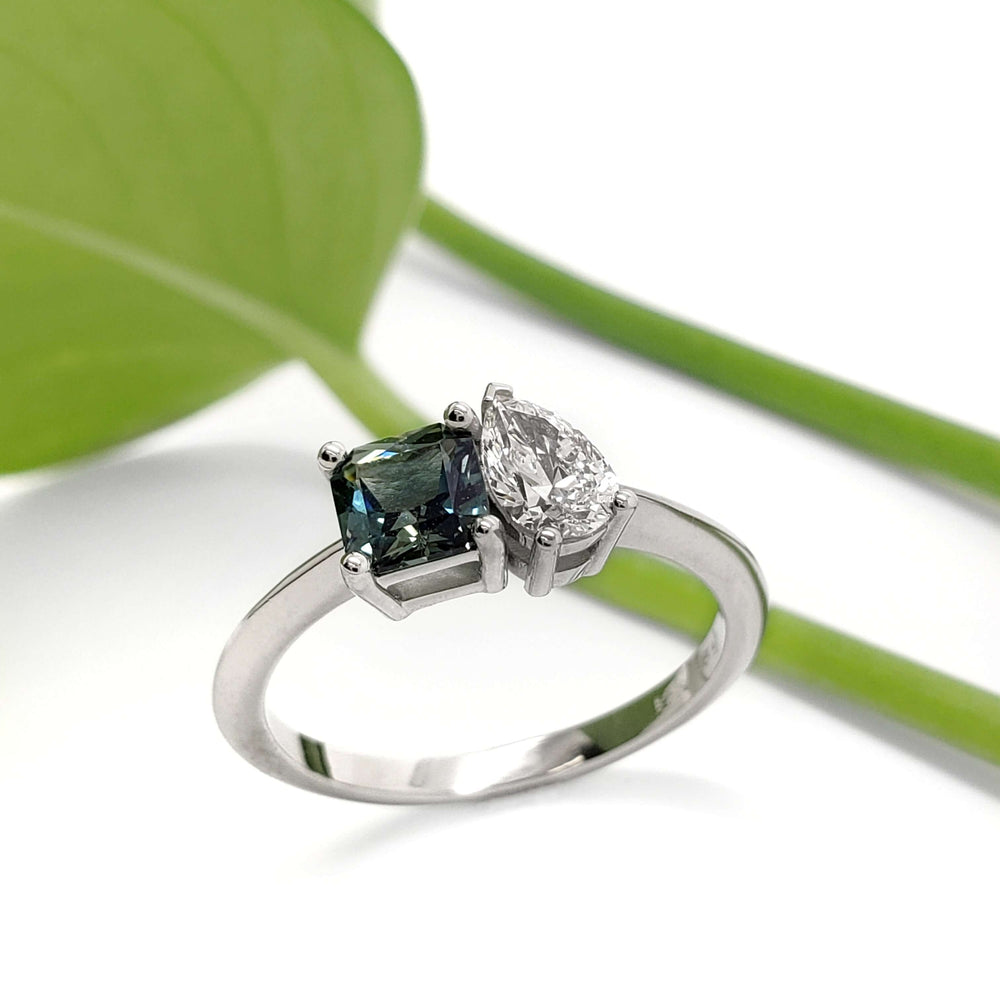 Handcrafted white gold ring with teal Australian sapphire and pear-shaped lab diamond, leaf background