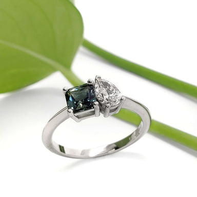 Handcrafted white gold ring with teal Australian sapphire and pear-shaped lab diamond, leaf background