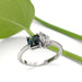 Handcrafted white gold ring with teal Australian sapphire and pear-shaped lab diamond, leaf background