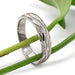 Handcrafted white gold wedding ring with bark texture, displayed on green stems