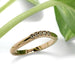 Handcrafted yellow gold chevron diamond wedding ring beside green leaves