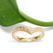 Handcrafted yellow gold chevron wedding ring with wheat engraving, shown with a green leaf