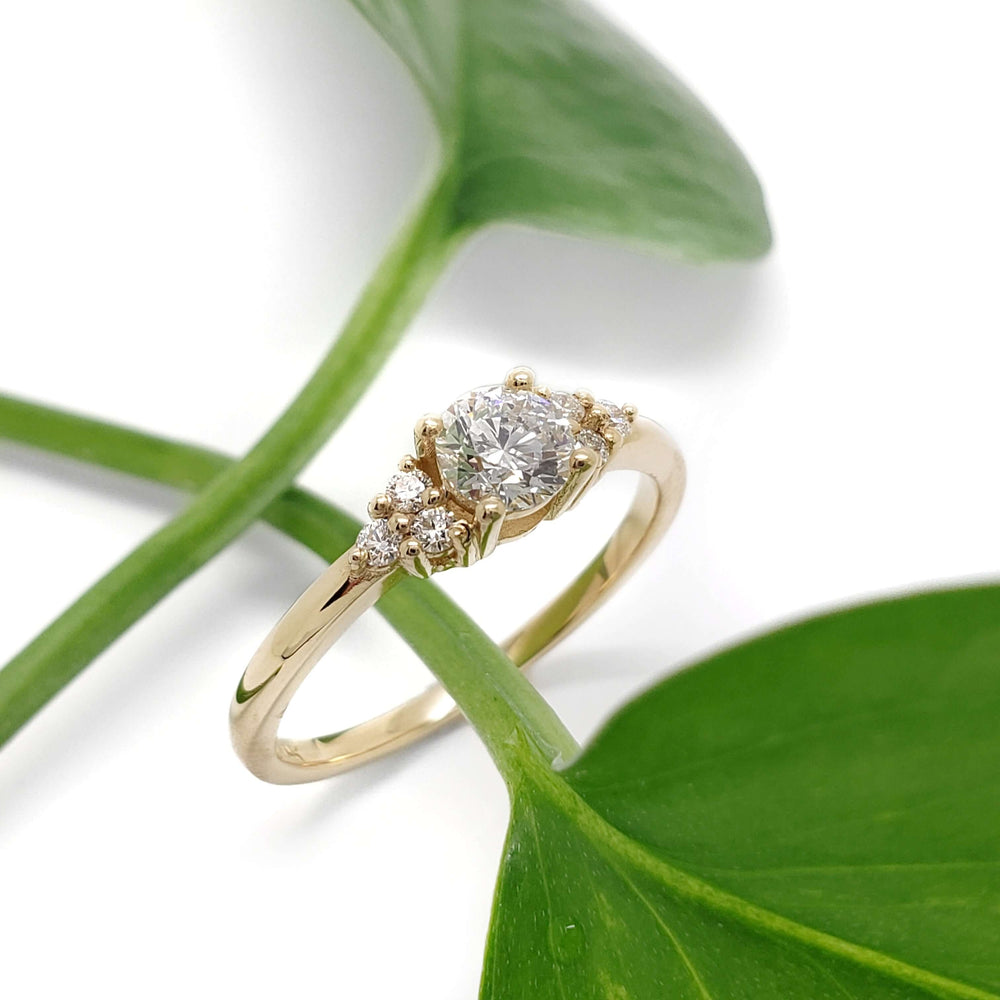 Handcrafted yellow gold diamond ring displayed with green leaves