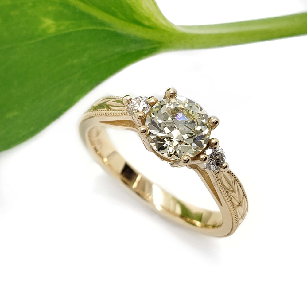 Handcrafted yellow gold engagement ring with old European diamond, leaf engraving, and accent stones