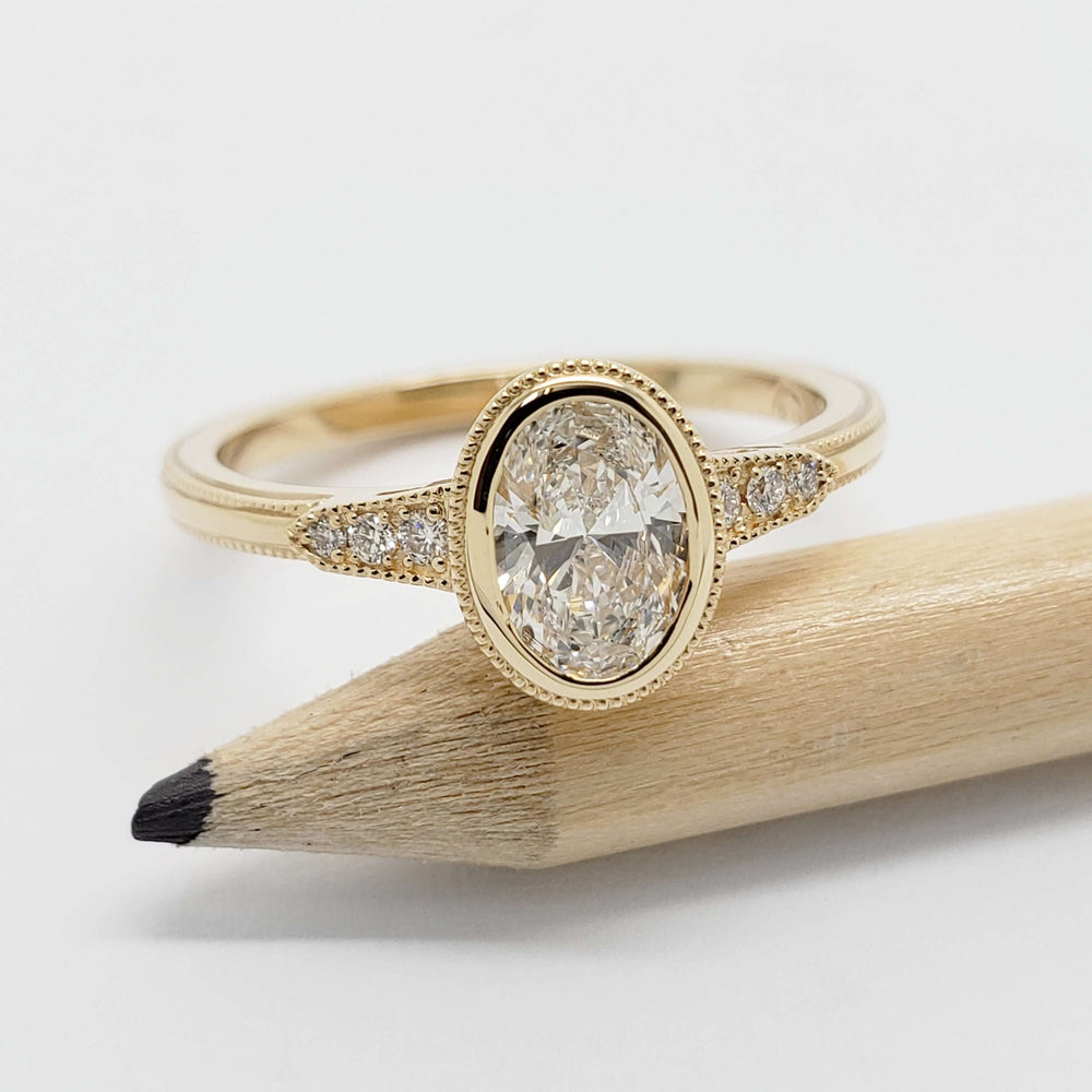 Handcrafted yellow gold engagement ring with oval lab diamond, shown next to a pencil