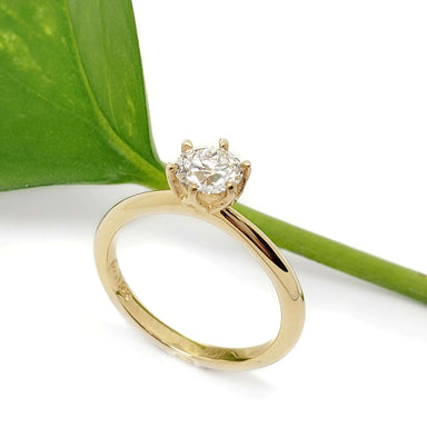 Handcrafted yellow gold lab-grown diamond engagement ring by a green leaf