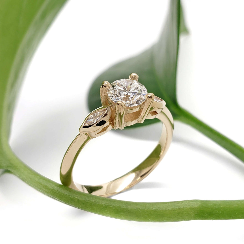 Handcrafted yellow gold lab diamond ring with marquise accents, styled with green leaf