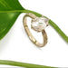 Handcrafted yellow gold pear lab diamond ring with engraved band beside a green leaf