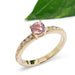 Handcrafted yellow gold ring with pink sapphire and diamonds, leaf in background