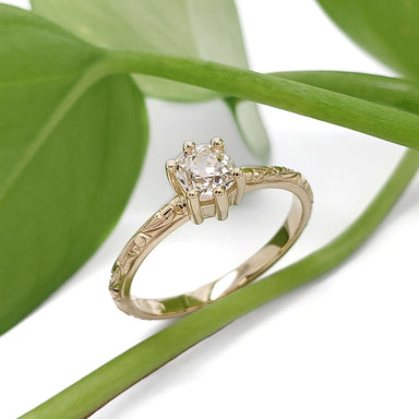 Handcrafted yellow gold ring with antique diamond, displayed with green leaves