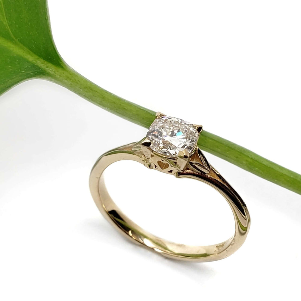 Handcrafted yellow gold ring with cushion lab diamond beside a green leaf