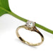 Handcrafted yellow gold ring with cushion lab diamond beside a green leaf