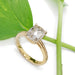 Handcrafted yellow gold ring with cushion rose cut lab diamond beside a green leaf