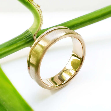 Handcrafted yellow gold wedding band with brushed texture and carved wave detail
