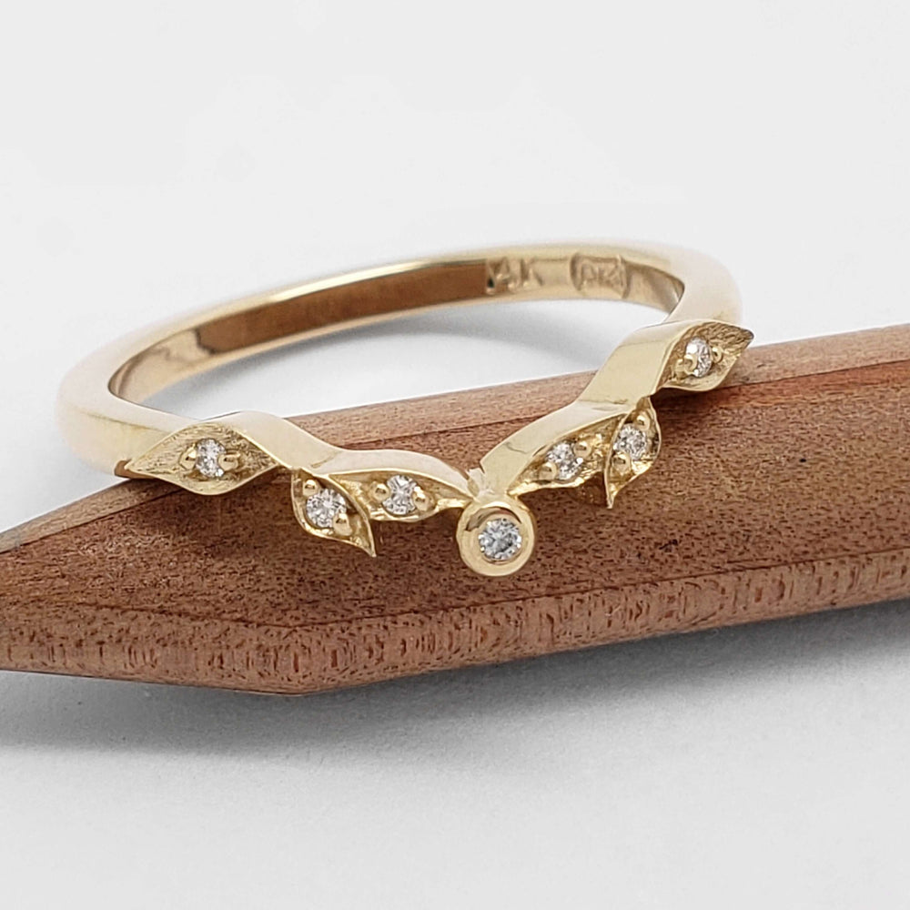 Handcrafted yellow gold wedding band with diamonds on a wood background