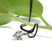 Heart-shaped lab diamond pendant in white gold with black chain, styled on a green leaf