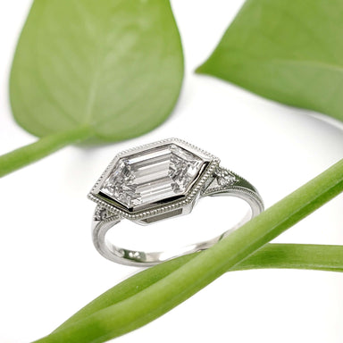 Hexagon lab diamond engagement ring in white gold displayed with green leaves