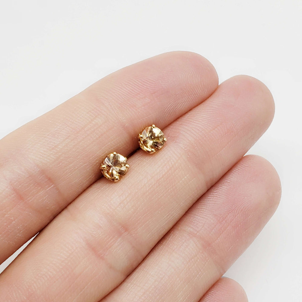 Imperial topaz 14kt yellow gold stud earrings shown on a hand for scale