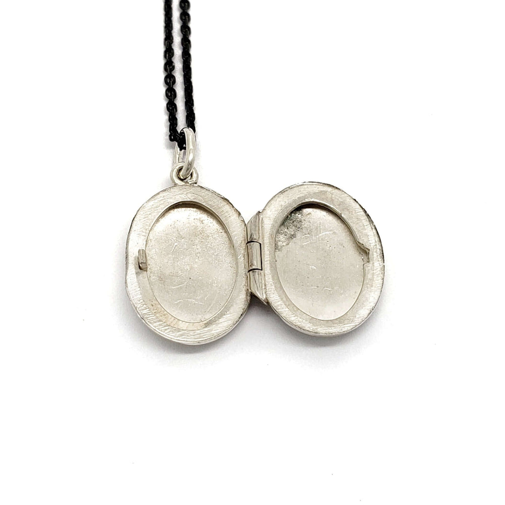 Open vintage oval sterling silver locket showing interior photo slots