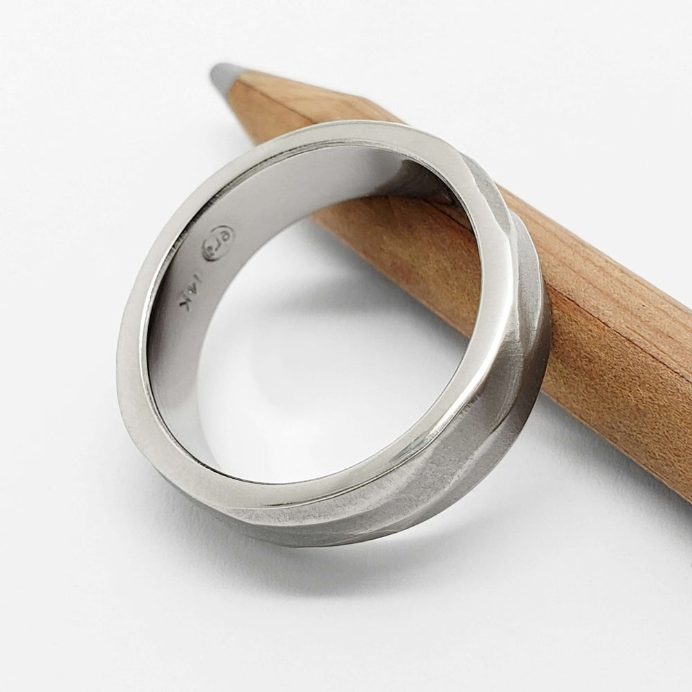 Interior view of 14k white gold topography wedding ring showing hallmark, on a pencil
