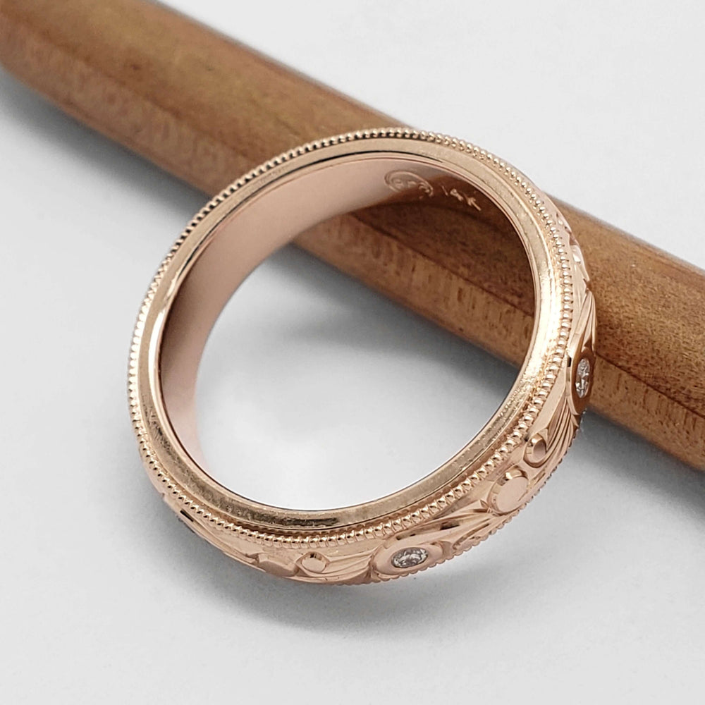 Interior view of 14kt rose gold wedding ring with scroll engraving and diamonds