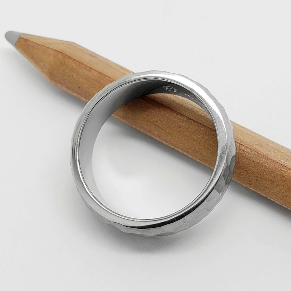 Interior view of 14kt white gold hammered wedding ring beside a pencil