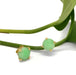 14kt yellow gold jade stud earrings displayed on green plant stems