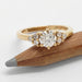 Yellow gold engagement ring with round lab diamond and accent stones, displayed on a pencil